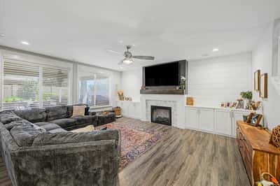 Warm and inviting family room features a custom fireplace, built-in cabinetry, luxury flooring, and oversized windows that create a bright, comfortable living environment.