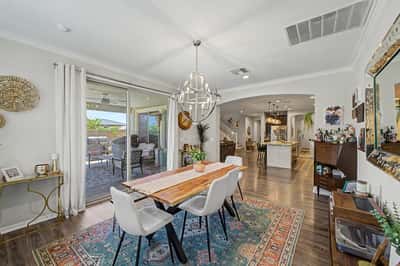 Beautiful dining room features a modern chandelier, luxury flooring, and direct patio access, creating an ideal setting for entertaining while connecting effortlessly to the open-concept kitchen.