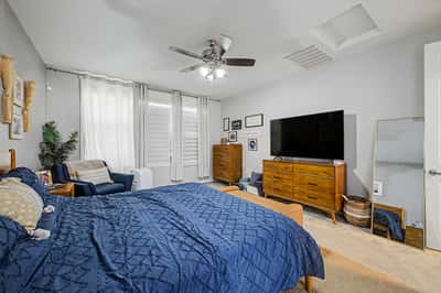 This alternate view of the primary bedroom showcases its spacious layout, natural light, ceiling fan, and flexible arrangement for oversized furniture.