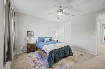 This bright secondary bedroom showcases generous dimensions, soft carpeting, ceiling fan, and flexible space suitable for guests, family members, or a home office.