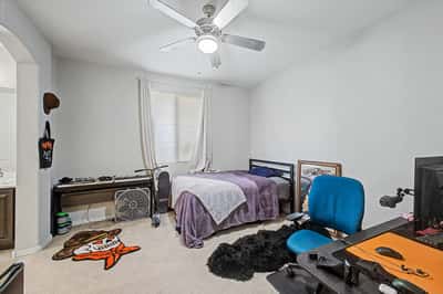 Spacious bedroom includes plush carpeting, ceiling fan, and natural light, offering flexibility for sleeping, working, or creating a personalized living space.