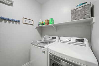 Laundry room offers modern appliances, convenient storage shelf, and efficient organization to simplify daily household tasks while maximizing functionality.