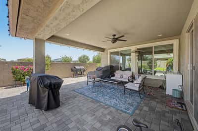 Large covered patio offers paver flooring, ceiling fan, multiple seating areas, and outdoor entertaining space that extends the living area into the beautifully landscaped backyard.