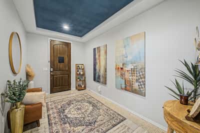 Beautiful foyer showcasing upgraded finishes, decorative tray ceiling, custom wood entry door, and a spacious layout that immediately welcomes family and guests.