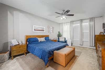 Spacious owner's suite offers plush carpeting, plantation shutters, neutral colors, and room for additional seating, creating a comfortable and inviting private retreat.