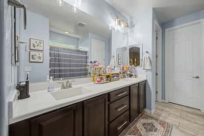 Stylish bathroom showcases a dual-sink vanity with quartz countertops, modern cabinetry, updated lighting, and generous storage for everyday convenience.