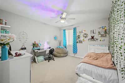 Spacious secondary bedroom provides ample room for guests, family, or a home office while featuring soft carpeting, natural light, and a ceiling fan for year-round comfort.