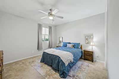 Spacious guest bedroom offers neutral d cor, plush carpeting, ceiling fan, and excellent natural light, creating an inviting retreat for visitors or everyday living.