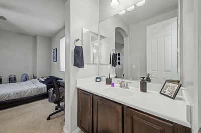 Alternate view of the private bathroom highlights the oversized vanity, abundant countertop space, modern fixtures, and functional design for everyday living.