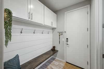 Functional entryway features custom built-in storage, bench seating, coat hooks, and upper cabinets, providing an attractive and organized everyday entry.