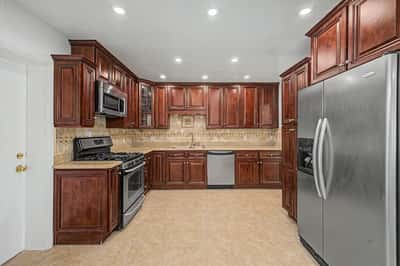 Well-appointed kitchen featuring extensive wood cabinetry, granite countertops, stainless steel appliances, decorative tile backsplash, and abundant prep space designed for both cooking and entertaining.