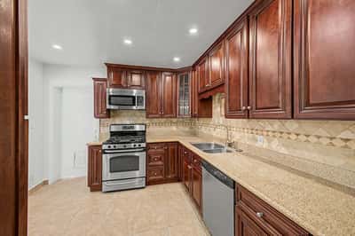 Beautifully appointed kitchen with granite countertops, extensive wood cabinetry, stainless steel appliances, decorative tile backsplash, recessed lighting, and generous workspace, creating a welcoming heart of this Phoenix home.