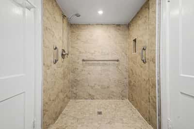 Beautifully tiled walk-in shower featuring grab bars, recessed storage niche, handheld showerhead, and modern finishes. Designed for comfort and convenience, this upgraded bathroom enhances the home's appeal.