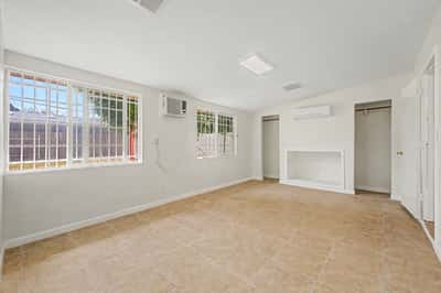 Spacious bedroom featuring large windows, tile flooring, mini-split air conditioning, open closet alcoves, and abundant natural light. This inviting retreat offers flexibility and everyday comfort in this Phoenix home.