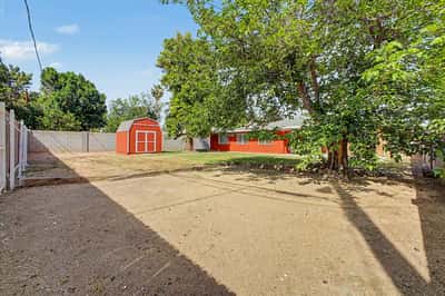 Backyard view highlighting mature trees, detached storage shed, and generous open space ready for landscaping, recreation, or entertaining. The spacious yard adds valuable flexibility to this Phoenix home.