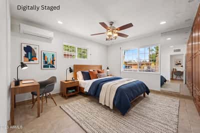 Digitally staged owner's suite featuring stylish furnishings, dedicated workspace, custom built-in storage, large windows, and an inviting layout that showcases the room's size and flexibility in this Phoenix property.