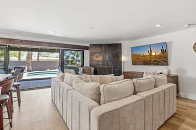 Open great room overlooks the private pool through expansive sliding glass doors, offering seamless indoor-outdoor living with direct access to the gourmet kitchen and entertaining spaces.