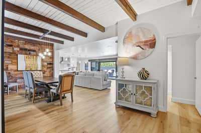 Spacious foyer connects the dining area and living spaces with warm wood accents, exposed beams, and an open layout that creates a welcoming first impression.
