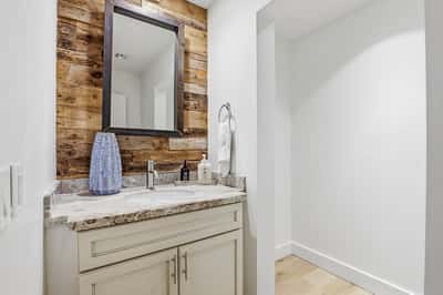 Beautifully updated powder room features contemporary fixtures, custom cabinetry, stone countertops, and rustic accent details, offering both style and functionality for guests.