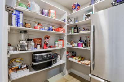 Walk-in pantry offers abundant shelving and organized storage, keeping the gourmet kitchen clutter-free while providing exceptional functionality for everyday living.