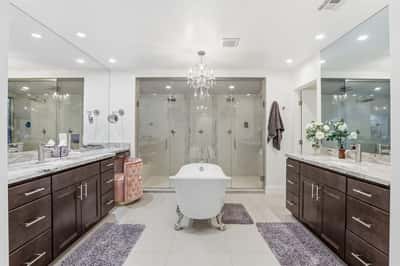 Resort-inspired primary bathroom features a freestanding soaking tub, dual vanities, oversized glass shower, designer chandelier, and upscale finishes that create a luxurious everyday retreat.