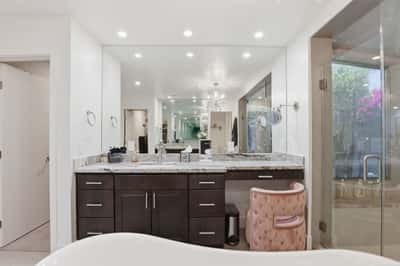 Beautiful vanity space offers dual sinks, stone countertops, custom cabinetry, and a dedicated makeup station, blending luxury and functionality in the spacious primary bathroom.