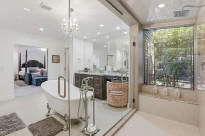 Oversized walk-in shower, freestanding soaking tub, and large windows combine to create a bright, relaxing spa-inspired bathroom with elegant finishes throughout.
