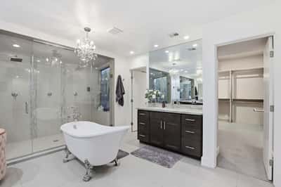 Stunning primary bath features dual vanities, a freestanding tub, expansive glass shower, and direct access to the walk-in closet, creating an exceptional owner's retreat.