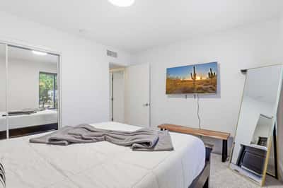 Well-appointed guest bedroom features large windows, mirrored closet doors, plush carpeting, and a bright neutral palette that complements the home's updated interior.