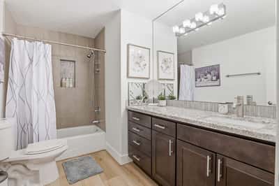 Renovated hall bathroom includes granite countertops, modern vanity, updated lighting, tiled shower and tub surround, and stylish finishes designed for both comfort and convenience.