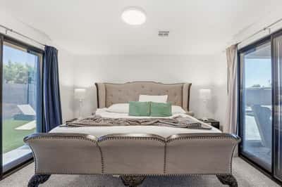 Spacious guest suite features elegant finishes, plush carpeting, dual sliding doors, and private access to the outdoor living spaces, creating a comfortable retreat in Scottsdale.