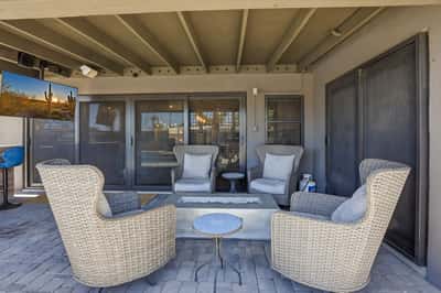 Covered patio is designed for entertaining with comfortable seating, a contemporary fire feature, paver flooring, and easy access to the home's open-concept interior.