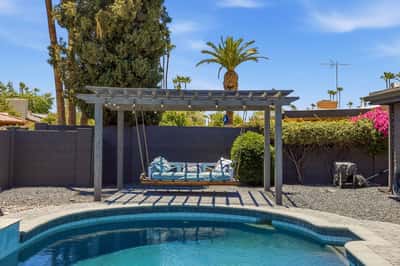 Elegant pergola with suspended daybed swing creates a peaceful outdoor retreat overlooking the pool area. A standout feature that enhances the Scottsdale backyard experience.