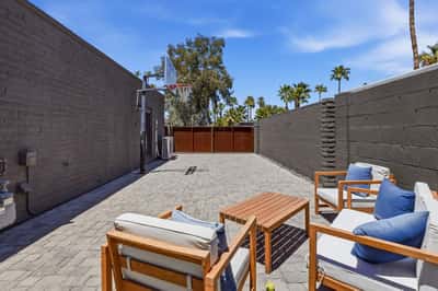 Versatile side yard features paver hardscape, basketball hoop, outdoor seating, and secure gated access, providing additional recreation and entertaining space for this Scottsdale property.