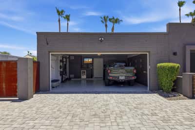 Exterior garage view showcases the oversized paver driveway, contemporary garage door, and organized interior with built-in cabinetry. A polished Scottsdale property with exceptional functionality.