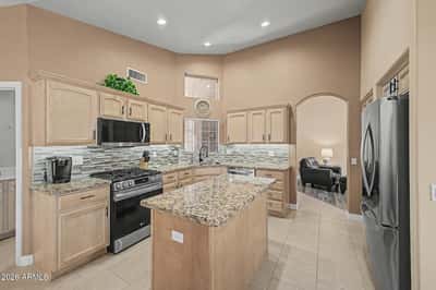 Prepare meals with ease in this spacious kitchen featuring granite countertops, stainless steel appliances, generous cabinetry, recessed lighting, and a large island designed for gathering and entertaining.