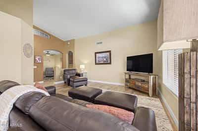 The spacious family room offers wood-look flooring, vaulted ceilings, abundant natural light, and an open layout perfect for relaxing, entertaining, or spending time with family in this Goodyear rental.