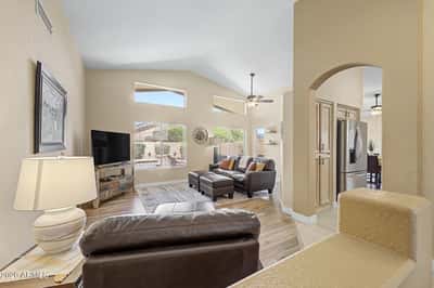 Large picture windows and soaring ceilings create an airy living space filled with natural light. The open design flows effortlessly into the kitchen, making everyday living both comfortable and inviting.