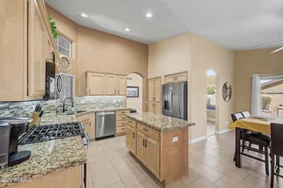 Designed for convenience, this open kitchen features granite countertops, stainless steel appliances, ample cabinet storage, tile flooring, and a center island that anchors the living and dining spaces.