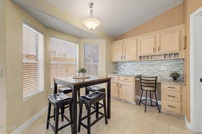 Enjoy meals or work from home in this sunny breakfast nook featuring bay windows, built-in cabinetry, and a convenient workspace. Natural light enhances the comfortable atmosphere throughout the day.