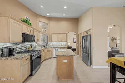 Featuring granite countertops, stainless steel appliances, a decorative tile backsplash, recessed lighting, vaulted ceilings, and a spacious island, this beautifully updated kitchen is designed for effortless entertaining and daily living.