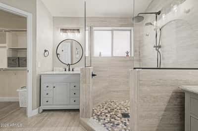 Experience luxury in the renovated primary bathroom featuring a custom tile shower, frameless glass enclosure, modern vanity, updated lighting, and elegant designer finishes throughout.