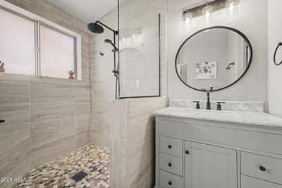 Beautifully upgraded with custom tile, a frameless glass shower, rainfall showerhead, pebble flooring, and contemporary vanity, this bathroom combines style and functionality for everyday comfort.