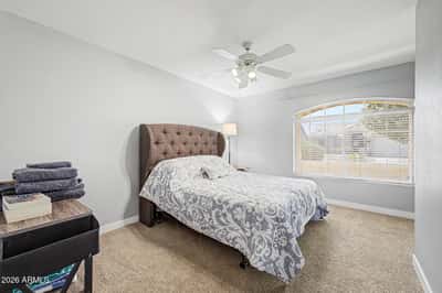 Featuring plush carpeting, neutral colors, and a large window, this welcoming bedroom offers a comfortable space for overnight guests, family members, or a private office.
