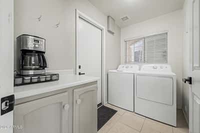 Complete with full-size washer and dryer, cabinetry, countertop space, and natural light, this dedicated laundry room offers convenience and efficiency for everyday household tasks.