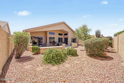 This inviting backyard combines mature landscaping, decorative rock, privacy fencing, and a large covered patio to create a peaceful outdoor retreat with minimal maintenance.