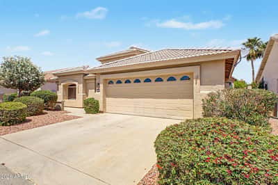 The front exterior features attractive desert landscaping, a welcoming covered entrance, and an attached two-car garage, offering a clean and inviting first impression in Goodyear.