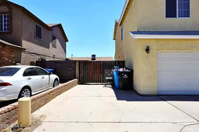 Side driveway with secure gated entry offers convenient additional parking and easy backyard access, complementing the attached two-car garage.