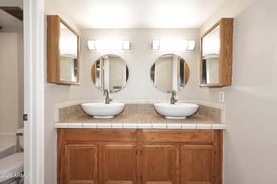 Spacious ensuite bathroom features dual vessel sinks, abundant cabinet storage, and a functional vanity designed for busy mornings.
