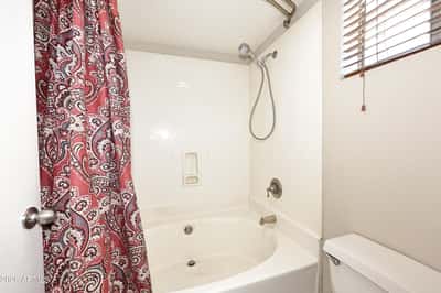 Private bathroom includes a full tub and shower combination with natural light and a practical layout that complements the spacious primary suite.